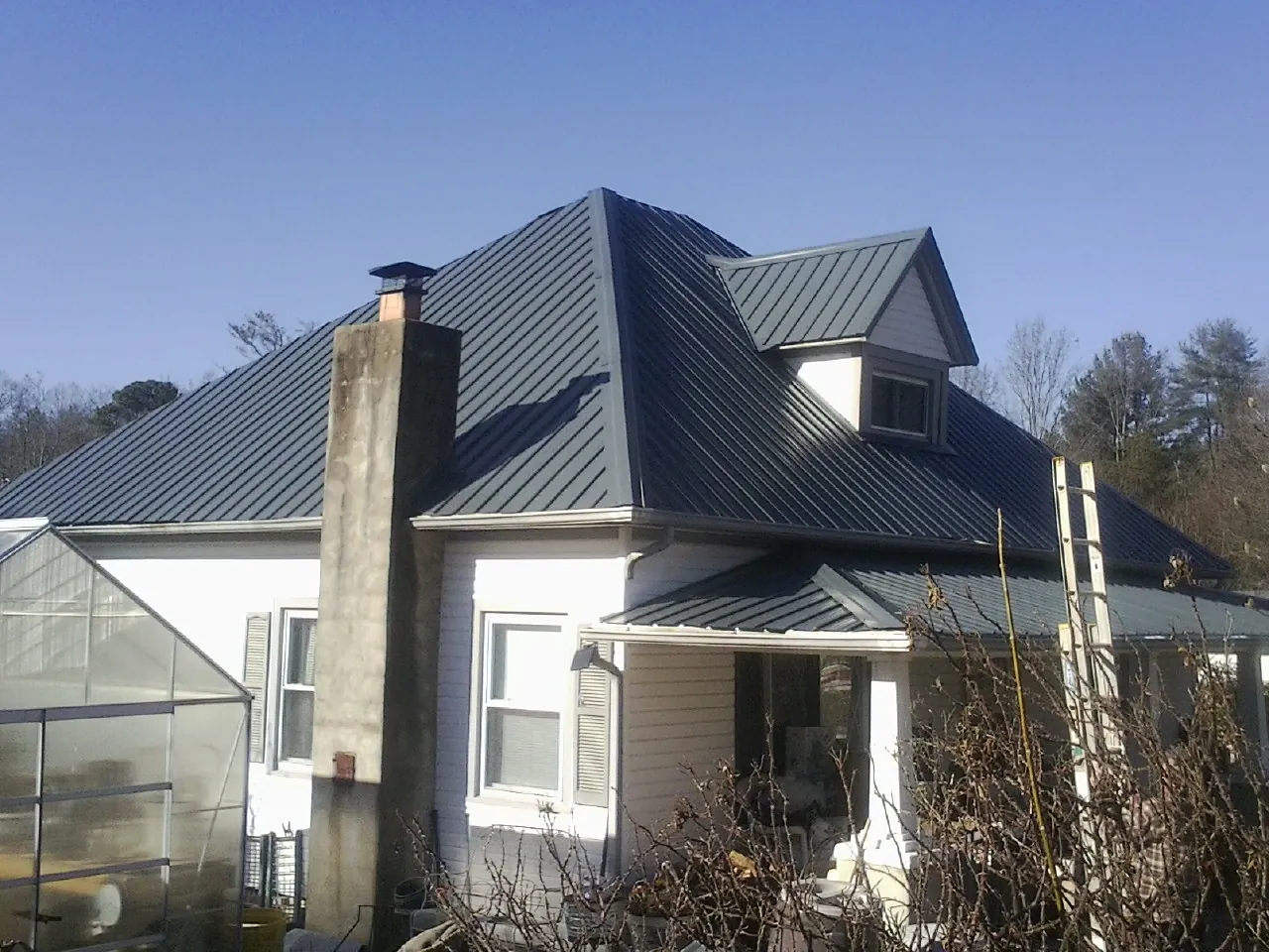 Dark blue standing seam metal roof on a white farmhouse with dormer — Slate & Tile Roof Repair by Roofing Brothers in Applegate