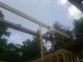Carpenter setting a ridge beam over a new addition frame — Ice Dam Removal by Roofing Brothers in Applegate