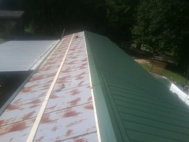Old rusted panels beside newly installed green metal roofing — Wind Damage Roof Repair by Roofing Brothers in Applegate